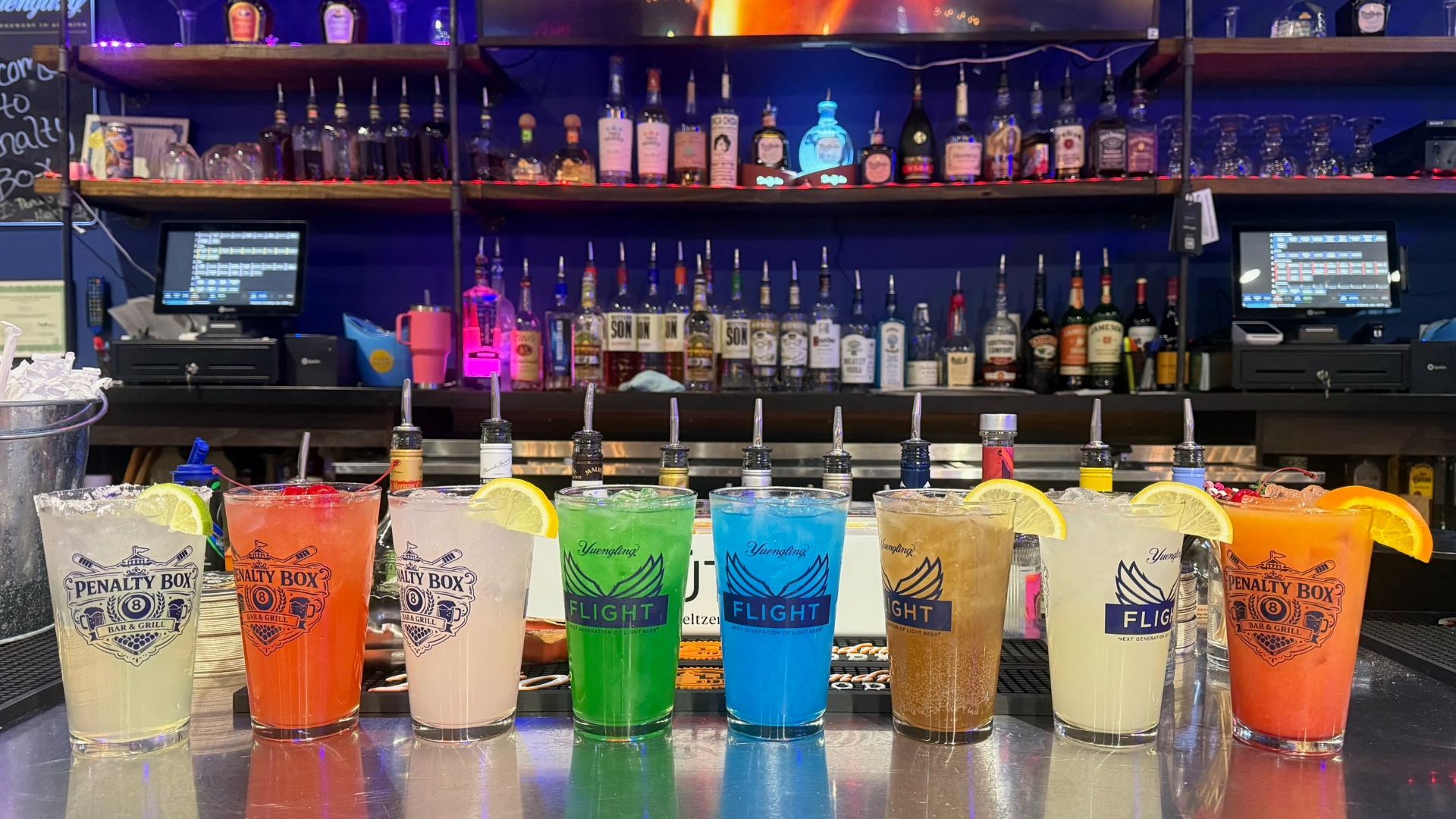 Signature cocktail lineup at The Penalty Box Bar & Grill — margarita, Power Play Sour, Lemon Shake-Up, Green Zone, Blues Blast, Slap Shot Tea, Penalty Drop and Scoreboard Sunrise
