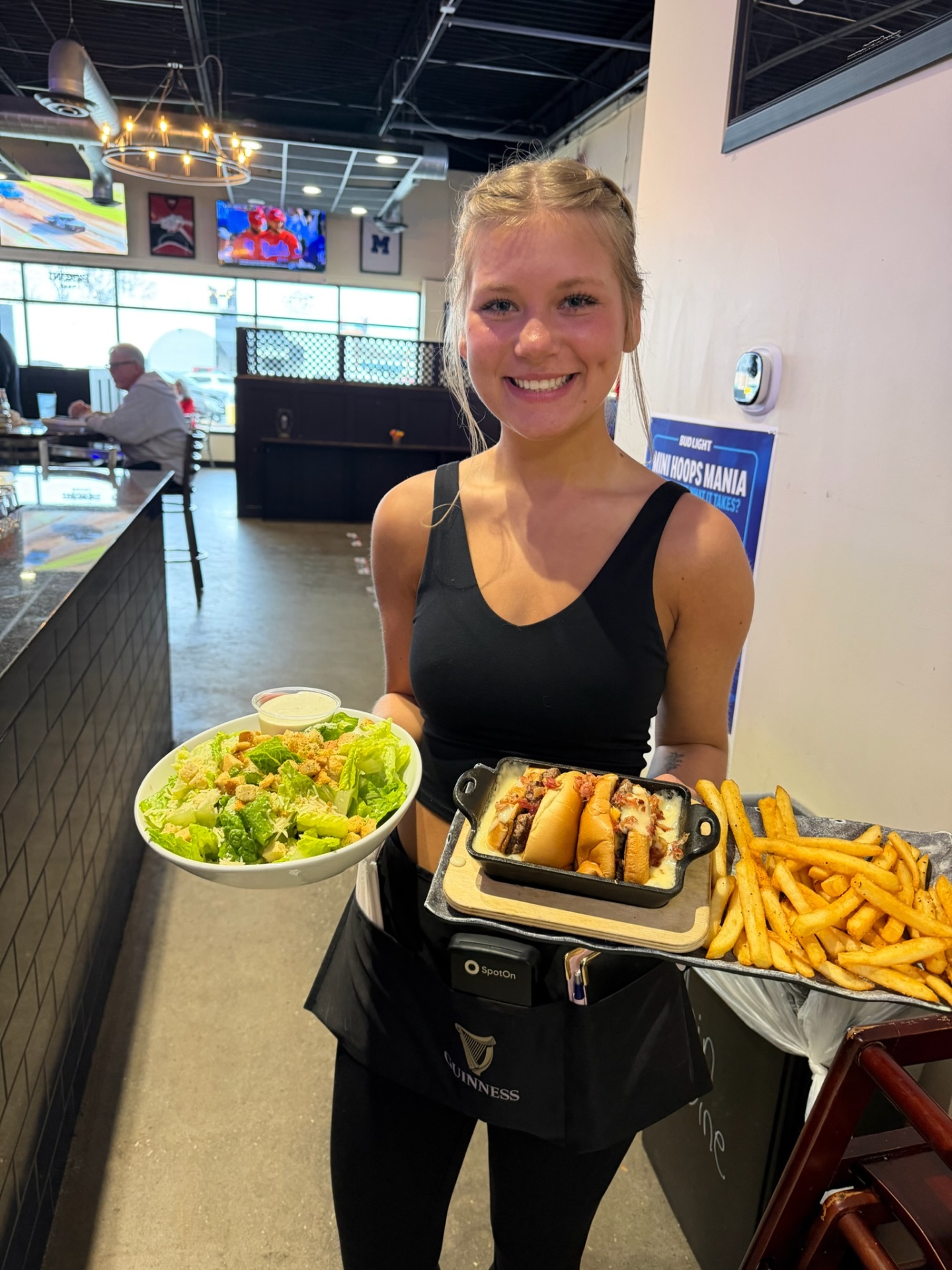 Penalty Box server carrying a Caesar salad and skillet pony shoe with seasoned fries